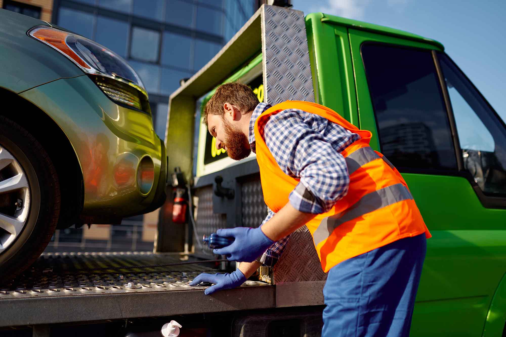 Tow Truck driving making sure car is strapped down - Apex Auto Center Towing Services